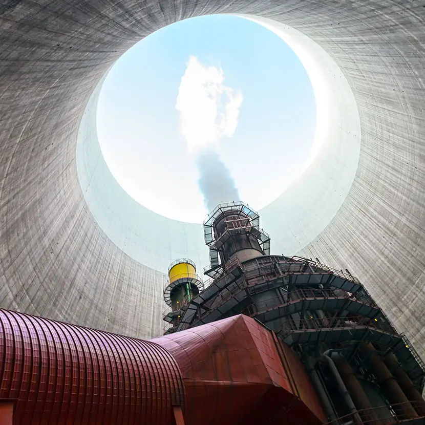 Upward view inside a nuclear cooling tower with steam rising from industrial equipment